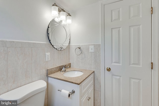 bathroom featuring toilet, tile walls, and vanity