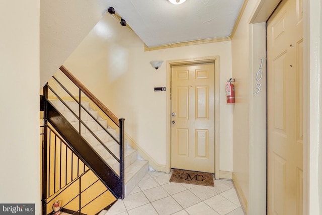 foyer entrance featuring light tile patterned floors, baseboards, and stairway