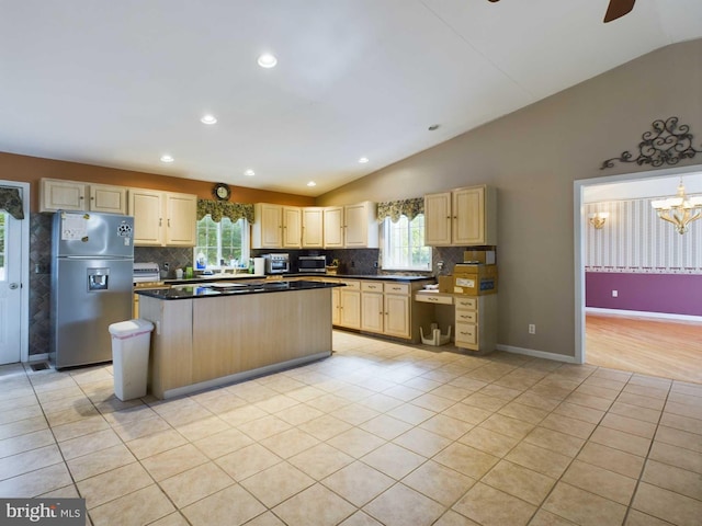 kitchen with lofted ceiling, light brown cabinetry, a kitchen island, and stainless steel fridge