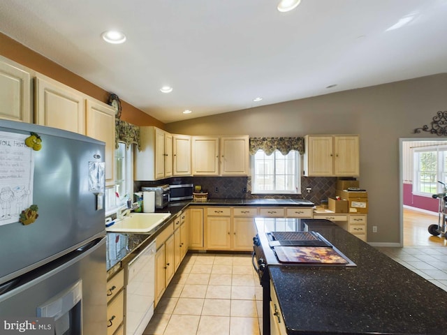 kitchen featuring light brown cabinetry, stainless steel appliances, lofted ceiling, and a healthy amount of sunlight