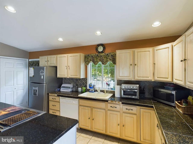 kitchen featuring lofted ceiling, light tile patterned floors, sink, appliances with stainless steel finishes, and decorative backsplash