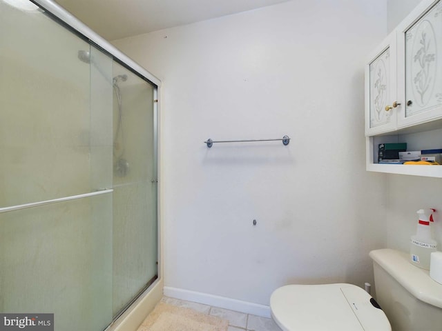 bathroom with tile patterned flooring, a shower with shower door, and toilet