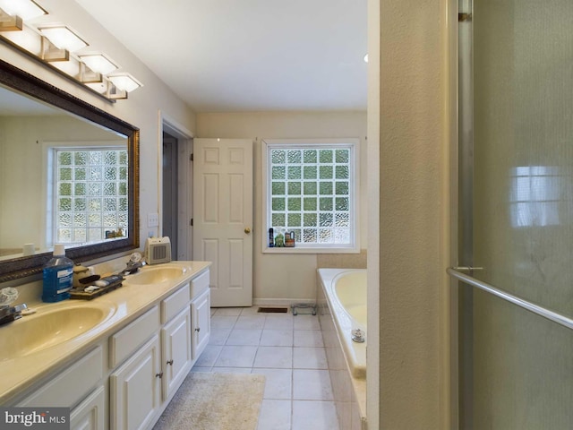 bathroom featuring vanity, a relaxing tiled tub, tile patterned floors, and a healthy amount of sunlight