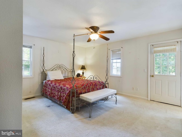 bedroom featuring ceiling fan, light carpet, and multiple windows