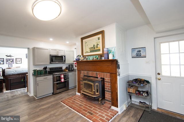 kitchen with hardwood / wood-style floors, stainless steel appliances, and a wood stove