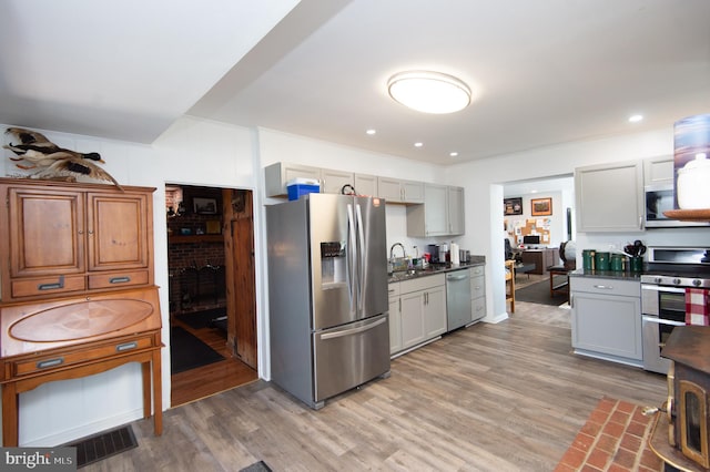 kitchen featuring a fireplace, wood-type flooring, stainless steel appliances, and sink