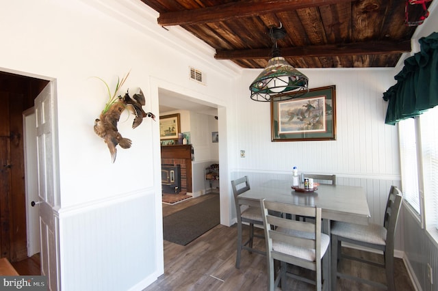 dining space featuring wood-type flooring, a fireplace, lofted ceiling with beams, and wooden ceiling