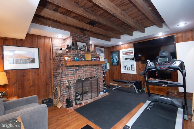 exercise area with a brick fireplace, hardwood / wood-style flooring, and wooden walls