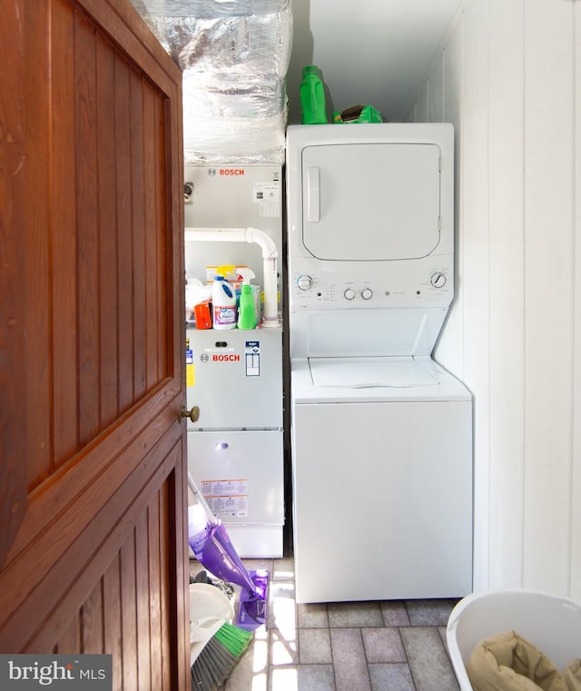 washroom with tile patterned flooring and stacked washing maching and dryer