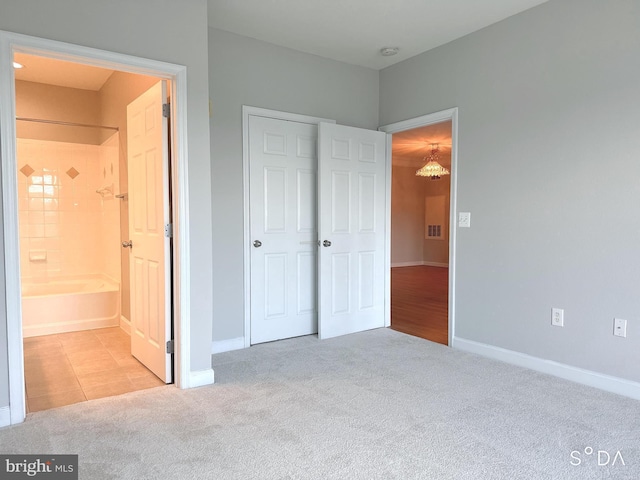 unfurnished bedroom featuring ensuite bath and light colored carpet