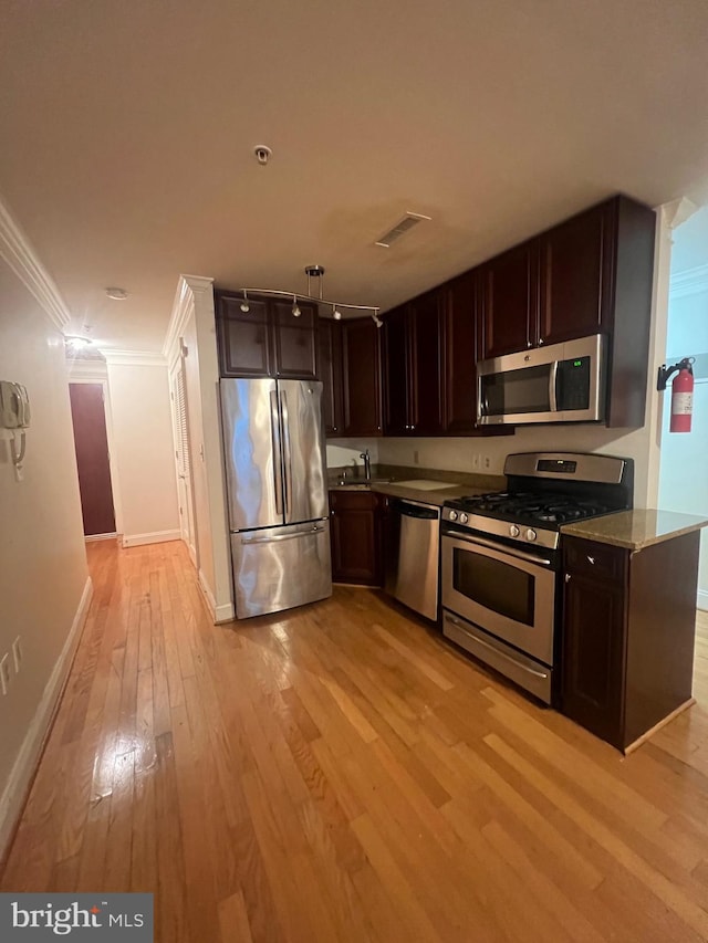 kitchen with ornamental molding, sink, appliances with stainless steel finishes, light stone counters, and light hardwood / wood-style floors