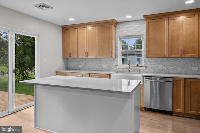 kitchen with light wood-type flooring, backsplash, dishwasher, and a center island