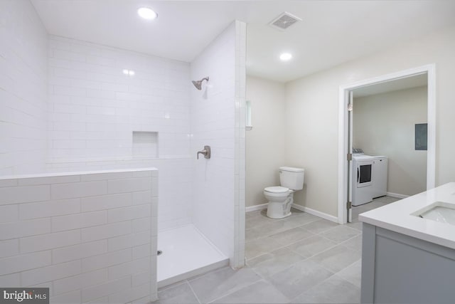 bathroom featuring tile patterned flooring, toilet, washer / clothes dryer, tiled shower, and vanity