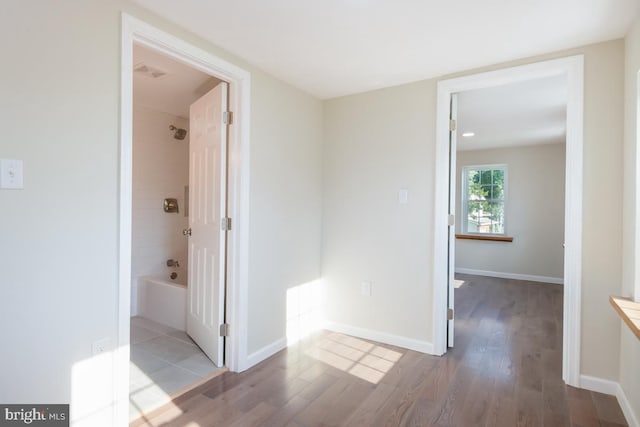 hall featuring visible vents, baseboards, and wood finished floors