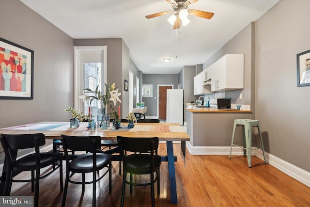 dining area with ceiling fan, light hardwood / wood-style flooring, and sink