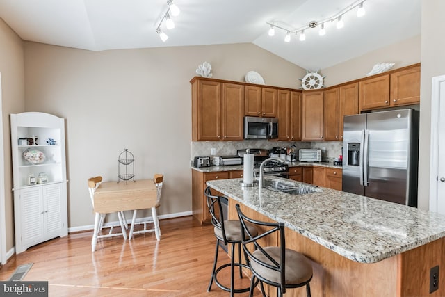 kitchen with appliances with stainless steel finishes, light wood-type flooring, sink, tasteful backsplash, and rail lighting