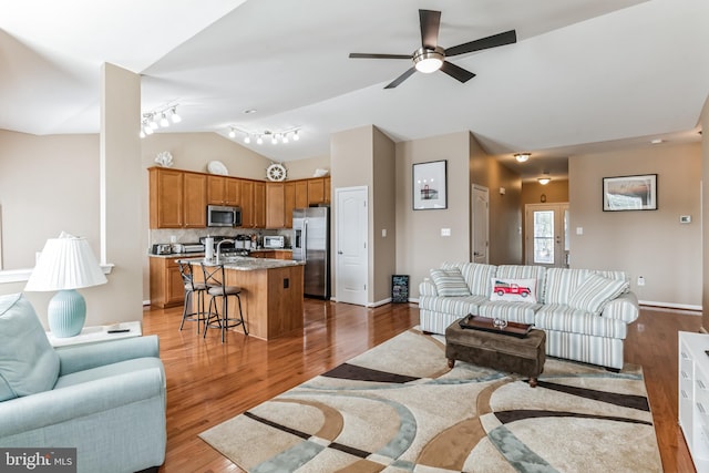 living room featuring ceiling fan, hardwood / wood-style flooring, track lighting, and lofted ceiling