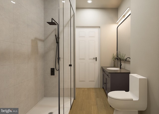 bathroom featuring wood-type flooring, toilet, a shower with shower door, and vanity