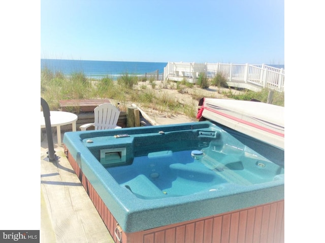 view of pool featuring a hot tub and a water view