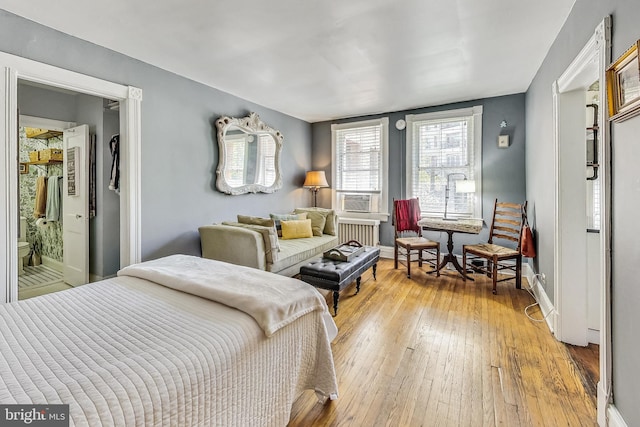 bedroom with radiator heating unit, cooling unit, and light hardwood / wood-style floors