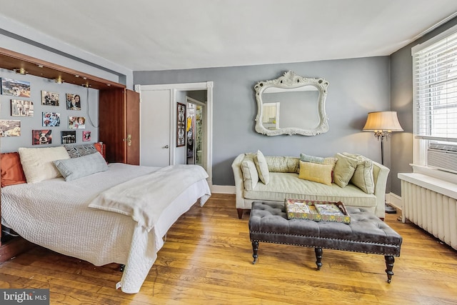 bedroom with a closet, hardwood / wood-style flooring, and radiator