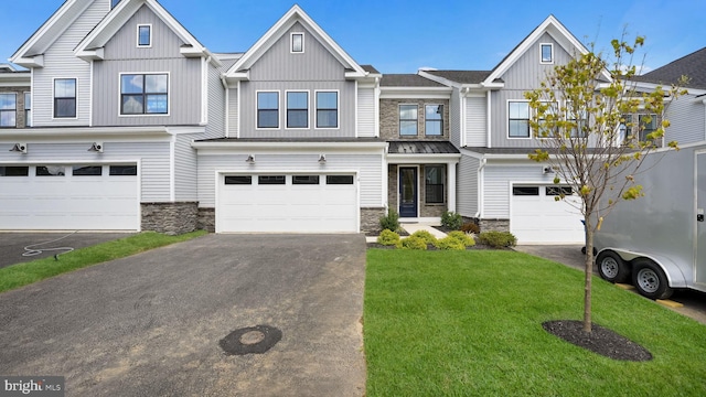 townhome / multi-family property featuring aphalt driveway, an attached garage, stone siding, a front lawn, and board and batten siding