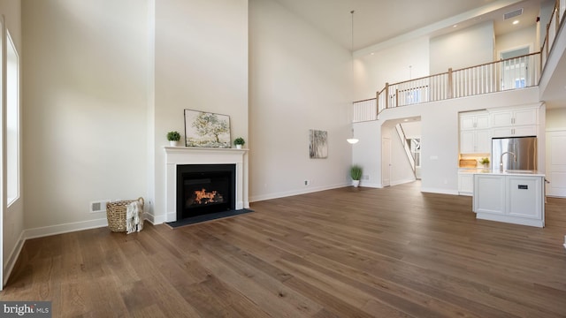 unfurnished living room featuring a fireplace with flush hearth, baseboards, visible vents, and dark wood-type flooring