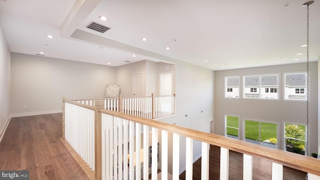 corridor with baseboards, wood finished floors, visible vents, and a healthy amount of sunlight