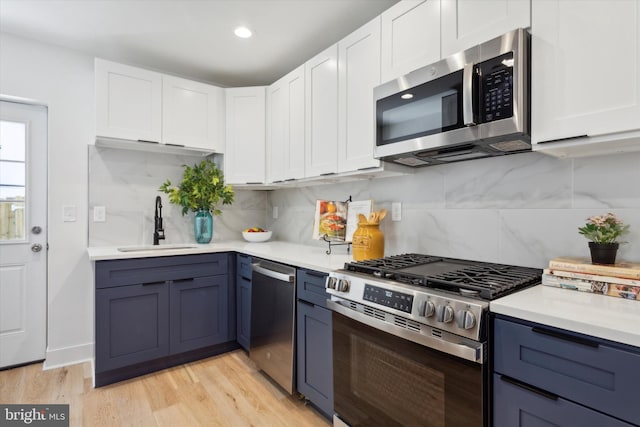 kitchen featuring decorative backsplash, appliances with stainless steel finishes, sink, and light wood-type flooring