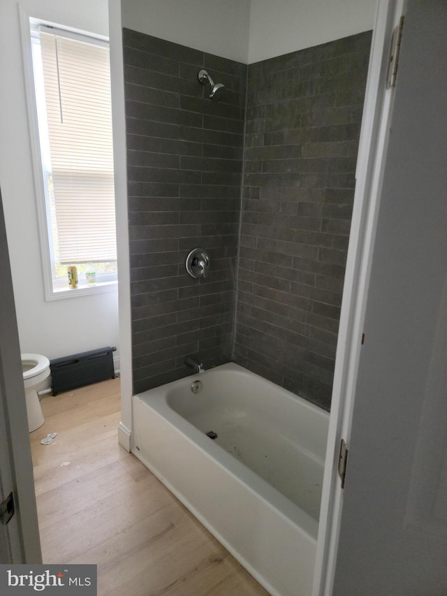 bathroom featuring toilet, hardwood / wood-style floors, and tiled shower / bath