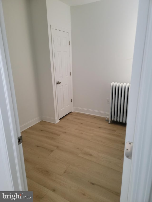 empty room featuring radiator heating unit and light hardwood / wood-style flooring