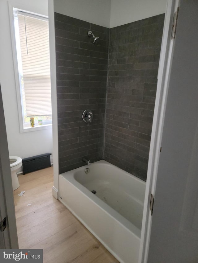 bathroom with tiled shower / bath combo, toilet, and hardwood / wood-style floors