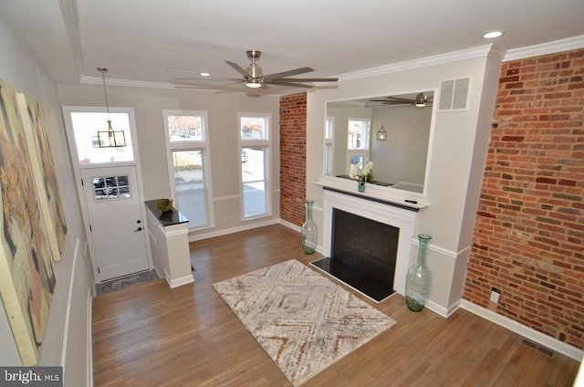 living room with hardwood / wood-style flooring, ornamental molding, ceiling fan, and brick wall