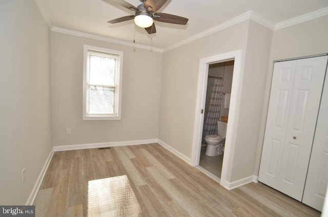 unfurnished bedroom featuring connected bathroom, ceiling fan, crown molding, light wood-type flooring, and a closet