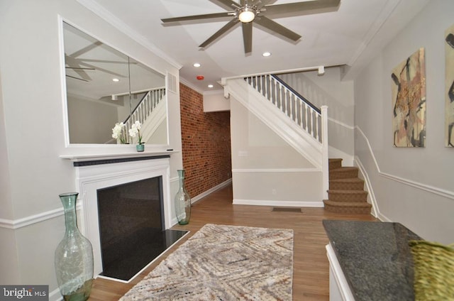 unfurnished living room featuring hardwood / wood-style flooring, brick wall, and ornamental molding