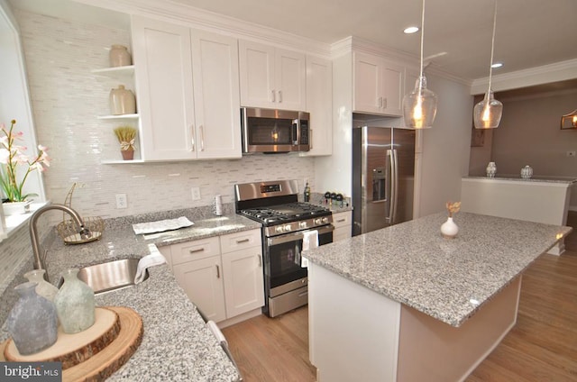 kitchen with white cabinetry, sink, hanging light fixtures, stainless steel appliances, and light stone countertops