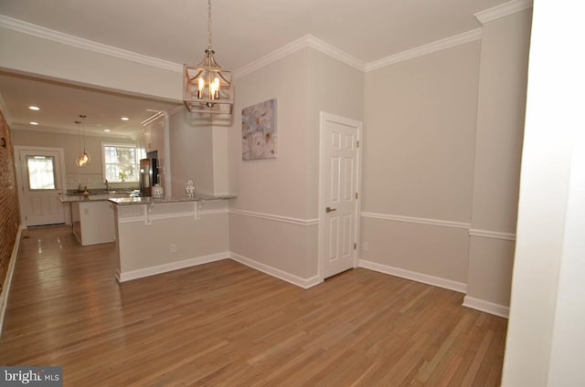 unfurnished room with crown molding, a notable chandelier, and light wood-type flooring