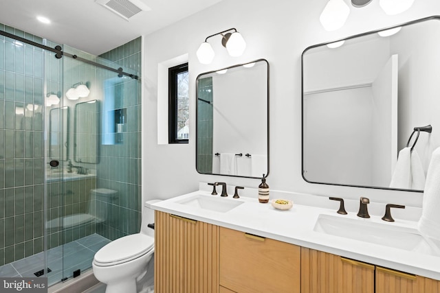 bathroom with toilet, vanity, and a shower with shower door