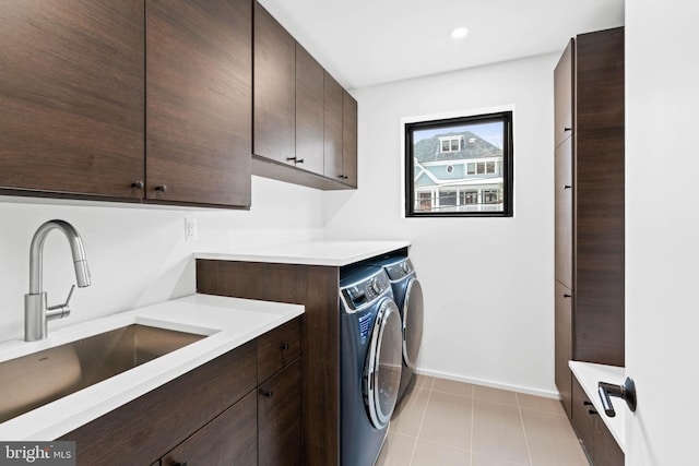 washroom featuring cabinets, washing machine and clothes dryer, light tile patterned floors, and sink