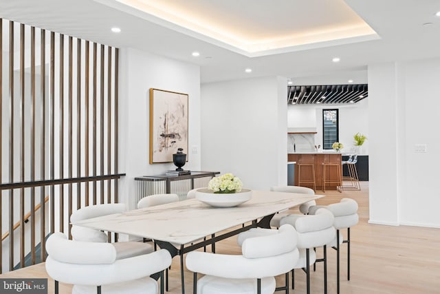 dining room featuring light hardwood / wood-style flooring and a tray ceiling