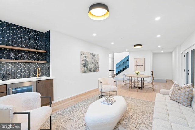 living room featuring light hardwood / wood-style flooring, indoor wet bar, and wine cooler