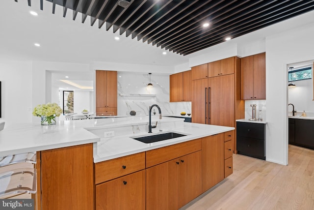 kitchen featuring sink, a kitchen bar, light hardwood / wood-style floors, backsplash, and plenty of natural light