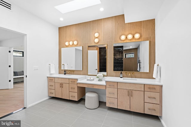 bathroom featuring vanity, wooden walls, tile patterned flooring, and a skylight