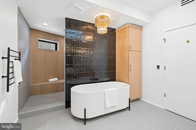 bathroom with a notable chandelier, a bath, and tile patterned floors