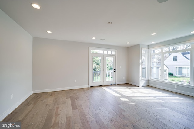 spare room featuring plenty of natural light, light wood-type flooring, and baseboards