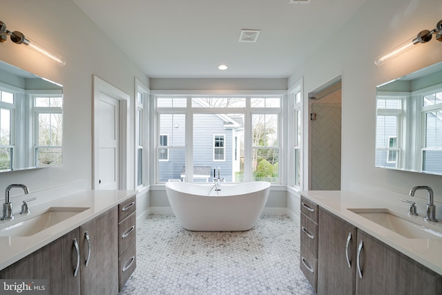 full bath featuring a freestanding tub, two vanities, a sink, and visible vents