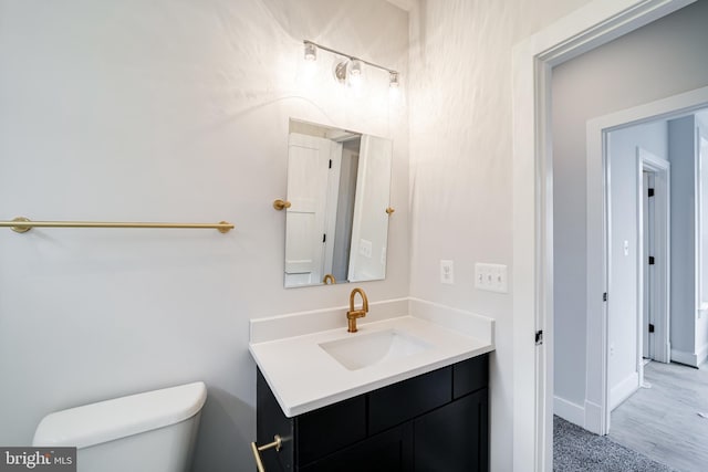 half bath featuring toilet, vanity, and baseboards