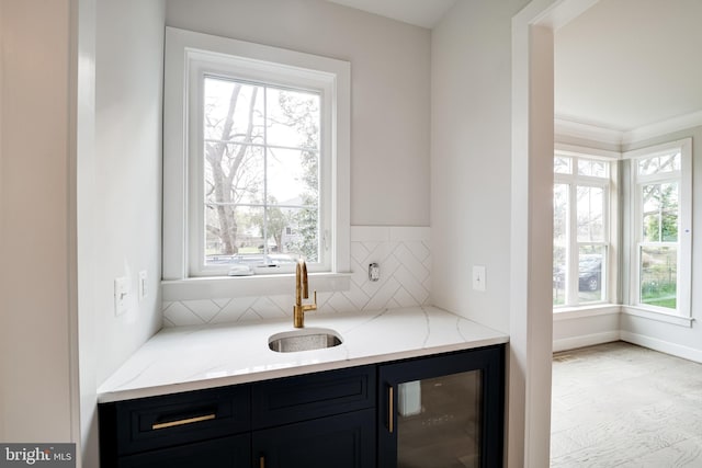 bar with beverage cooler, baseboards, a sink, and decorative backsplash