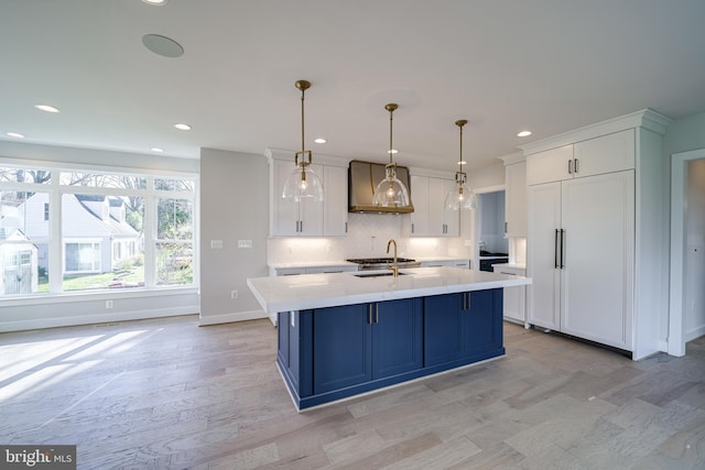 kitchen featuring white cabinets, decorative backsplash, light countertops, pendant lighting, and a sink