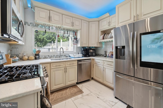 kitchen with appliances with stainless steel finishes, cream cabinets, light tile patterned floors, backsplash, and sink